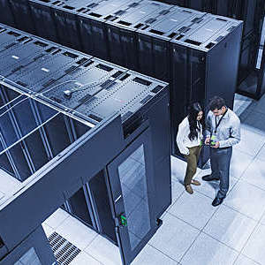 High-angle view of two technicians talking in a server room.