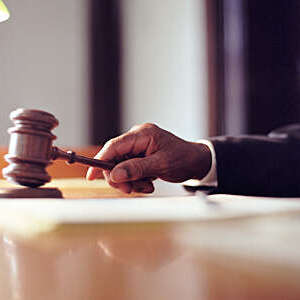 Male judge striking gavel in courtroom, close-up.