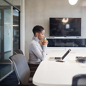 Side view of mature businesswoman looking at laptop and thinking.