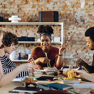 Young people of different backgrounds and cultures enjoy a friendly chat over lunch.